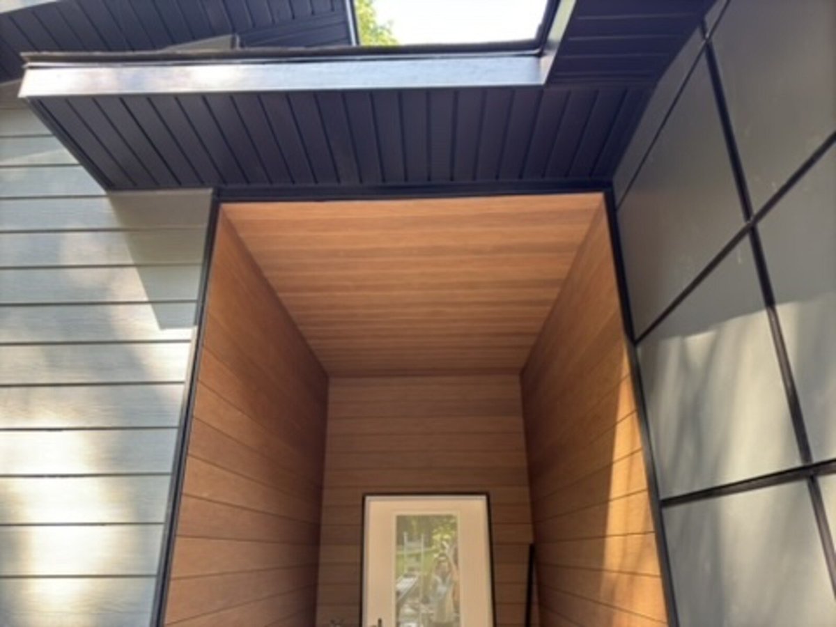 Covered entranceway with wood detailing in a modern custom home by R Value Homes, West Michigan