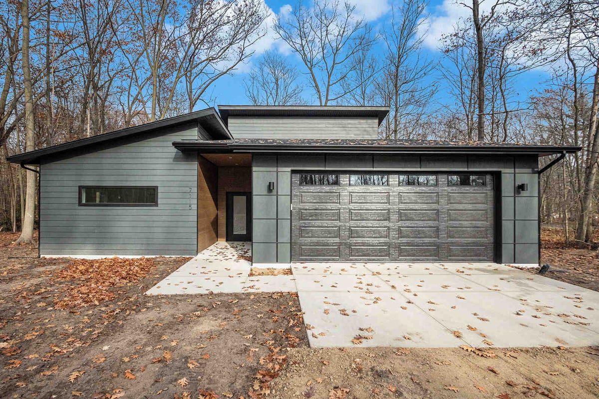 Custom-built modern home exterior in West Michigan by R Value Homes, surrounded by fall foliage