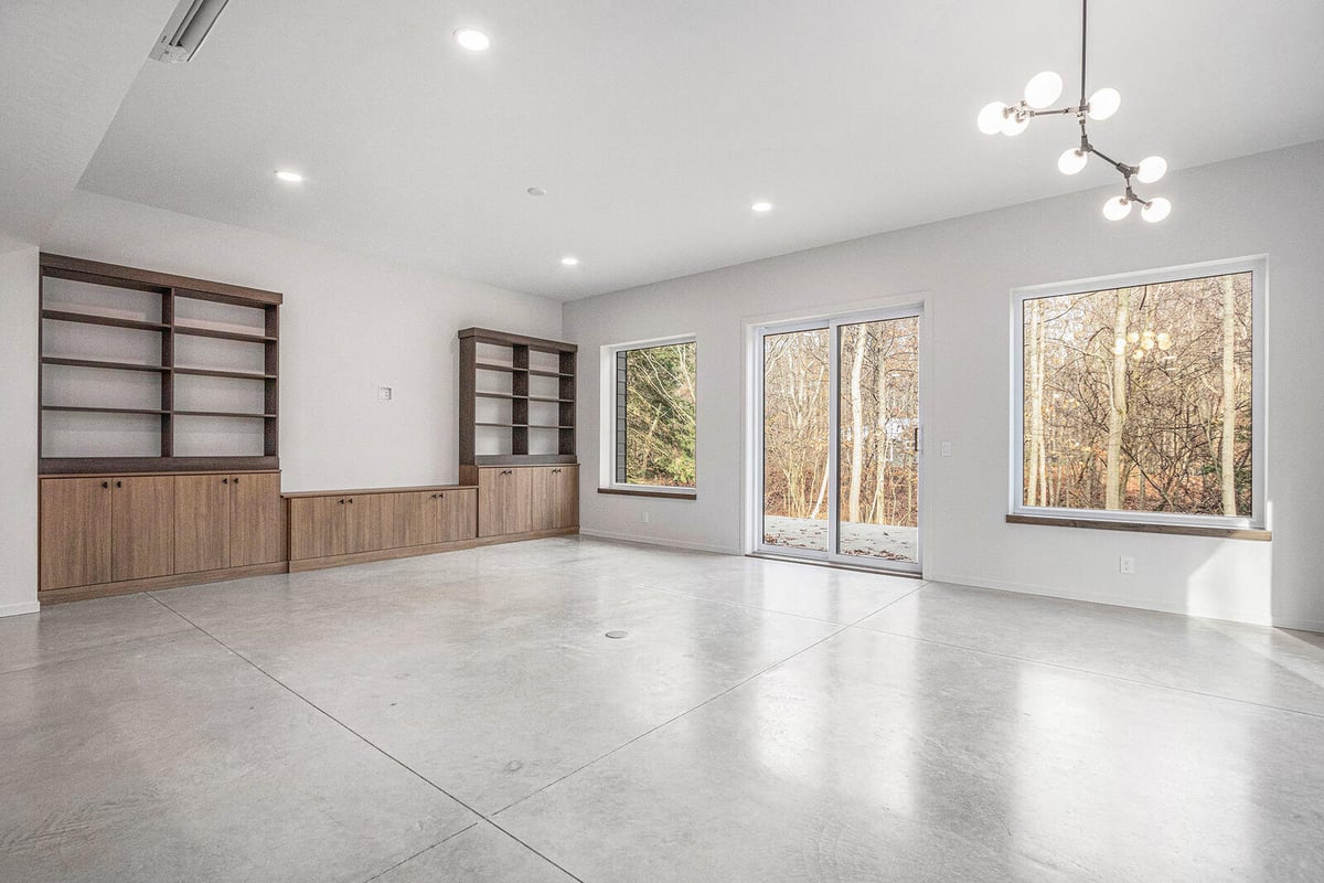 Minimalist living room with built-in shelving and large windows in a West Michigan custom home by R Value Homes