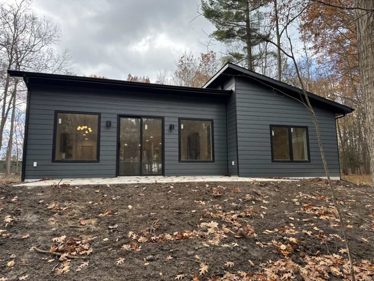 Rear view of a modern custom home by R Value Homes in West Michigan, surrounded by autumn trees