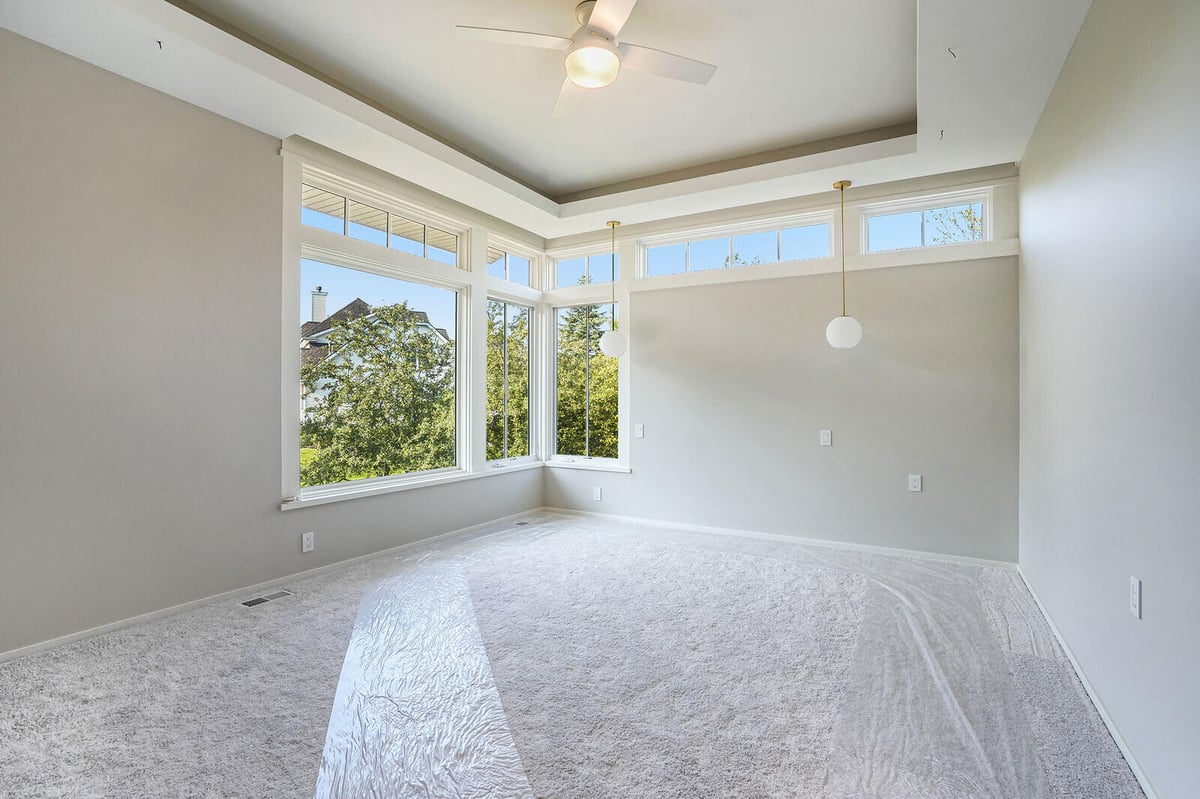 Bright bedroom with large corner windows and tray ceiling, built by R Value Homes in West Michigan