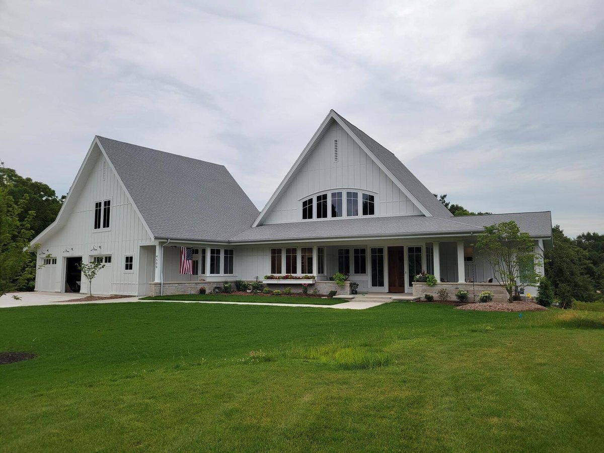 Front view of a modern farmhouse with lush green lawn, custom-built by R Value Homes in West Michigan