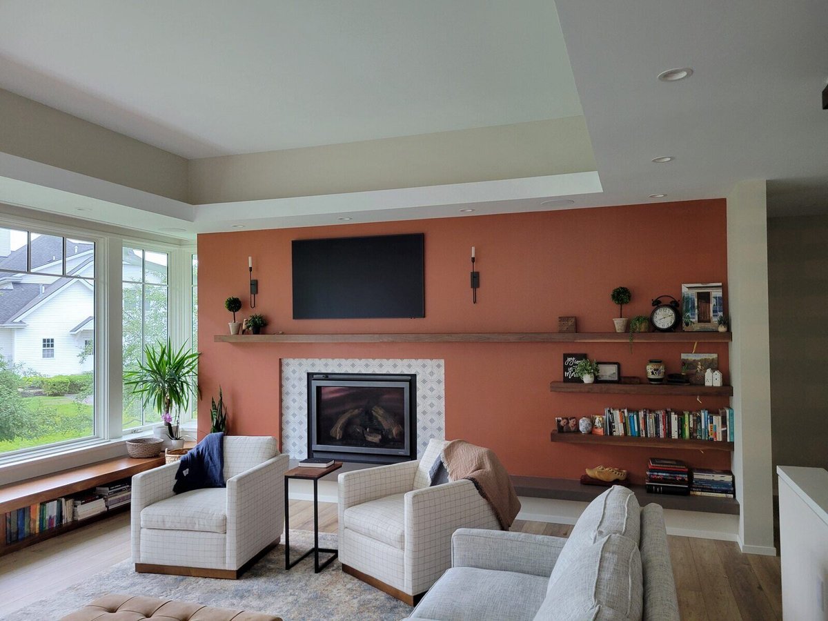 Modern living room with a cozy fireplace, built-in shelving, and large windows, designed by R Value Homes in West Michigan