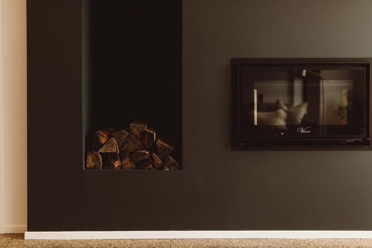Contemporary black fireplace with wood storage in a custom home by R Value Homes, West Michigan