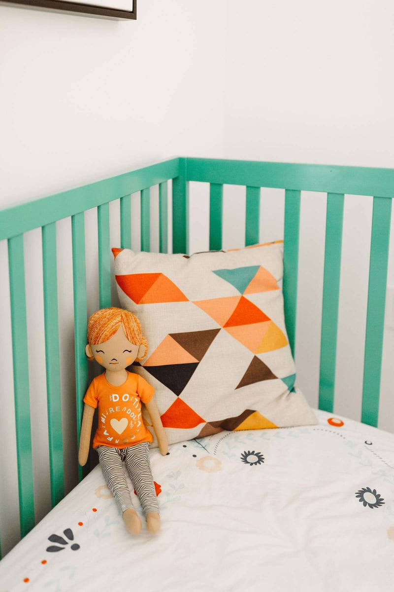Crib with a colorful geometric pillow and doll in a custom home by R Value Homes in West Michigan