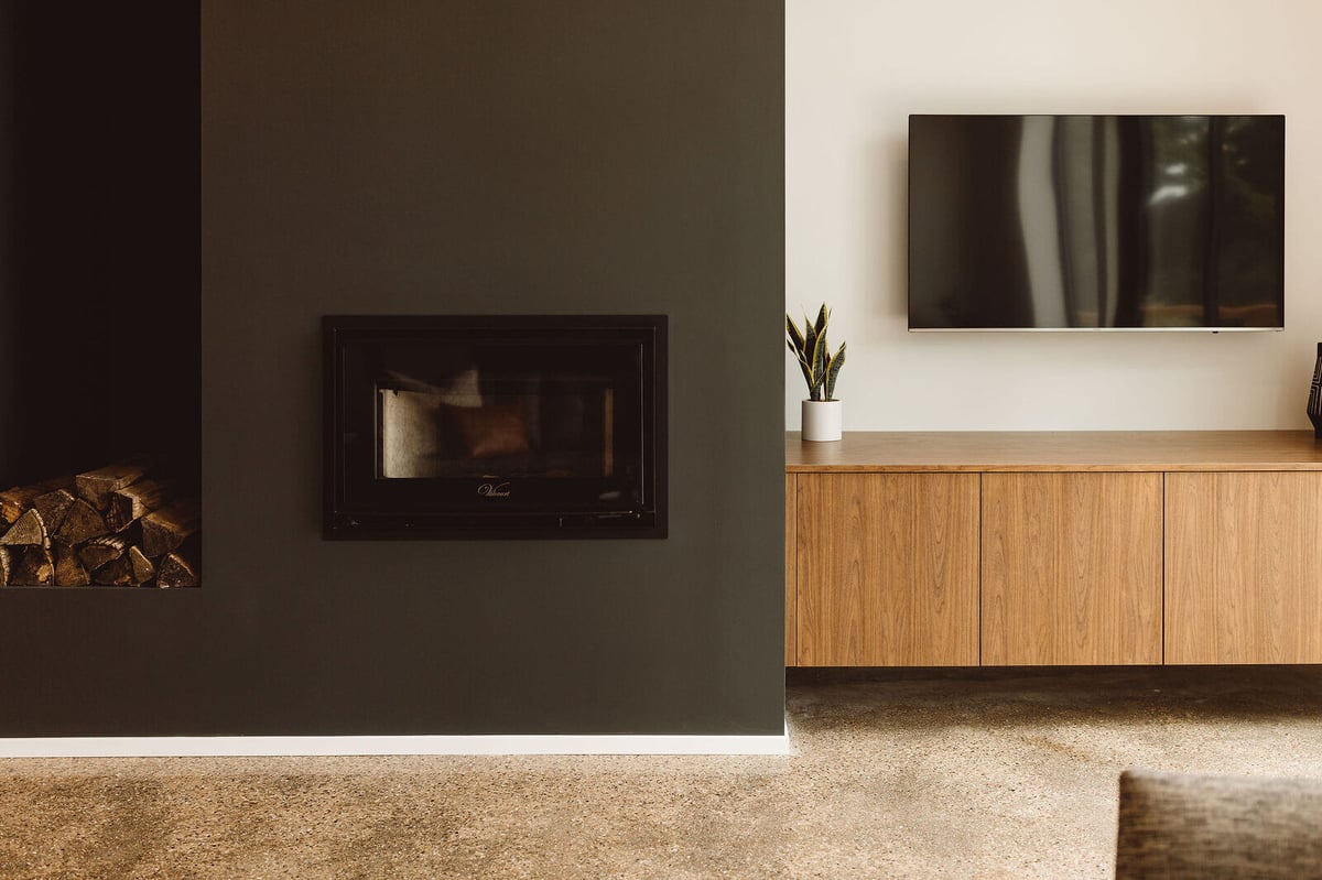 Minimalist living room with a dark fireplace in a custom home by R Value Homes in West Michigan