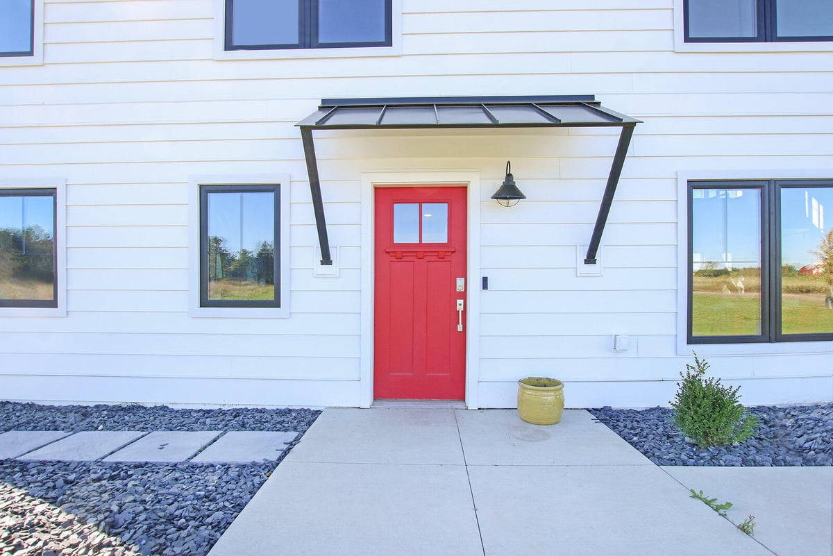 Front entryway of a custom-built home by R-Value Homes in West Michigan, featuring a red door and modern black awning