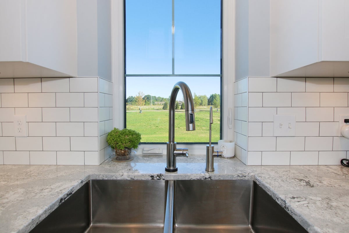 Kitchen sink view from a custom West Michigan home by R-Value Homes, overlooking lush greenery