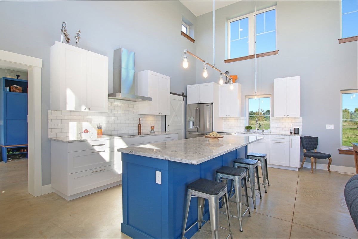 Modern kitchen with blue island and white cabinetry in a custom-built West Michigan home by R-Value Homes