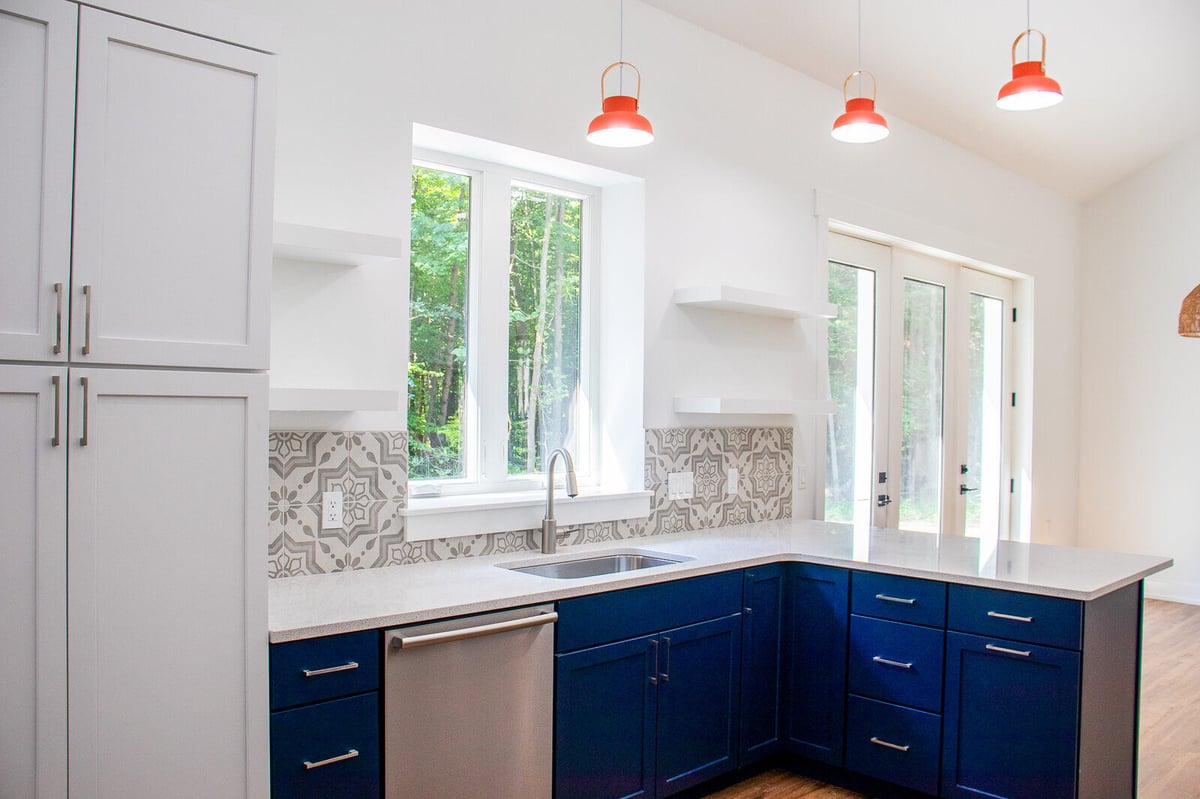 Kitchen in a custom West Michigan home by R-Value Homes, featuring blue cabinetry and decorative backsplash