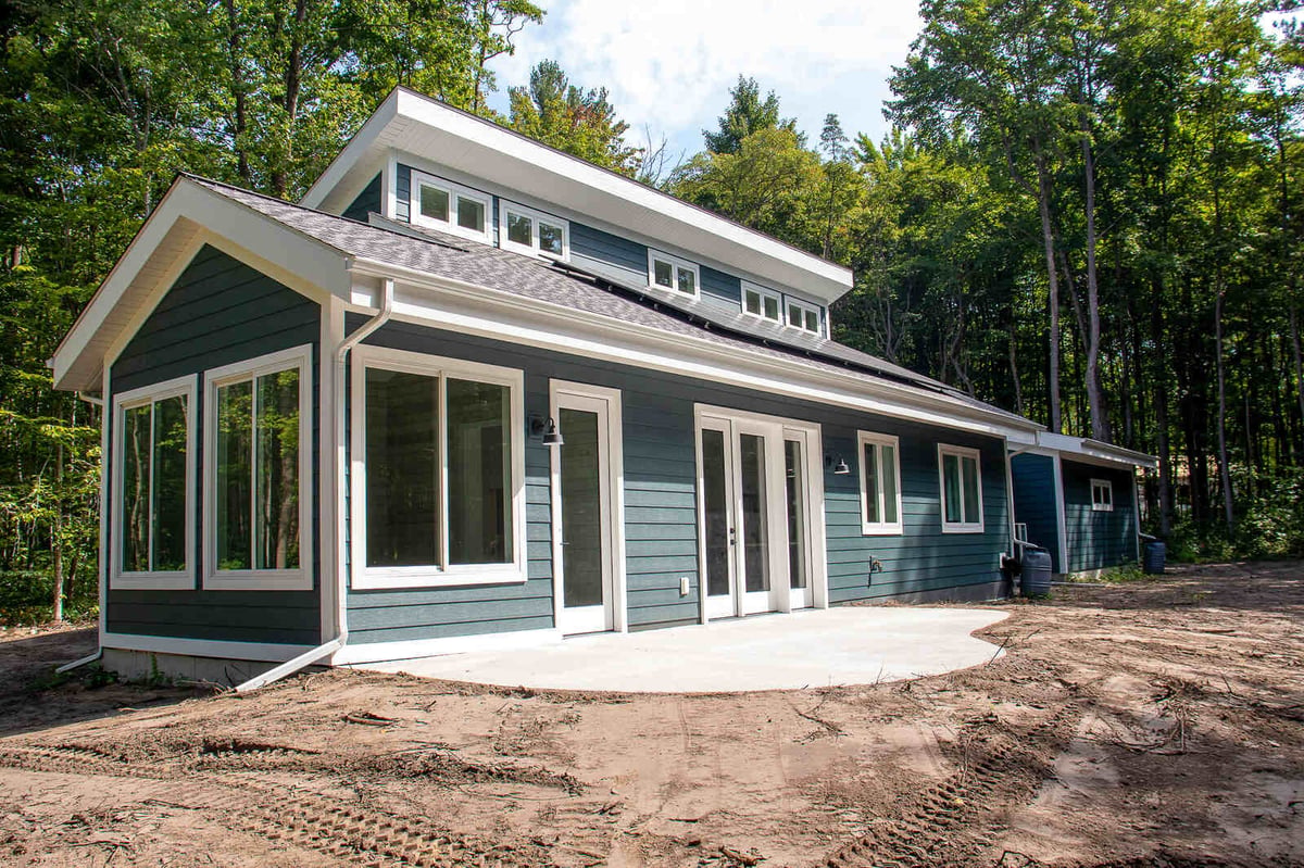 Rear exterior view of a custom-built West Michigan home by R-Value Homes, featuring large windows and patio access