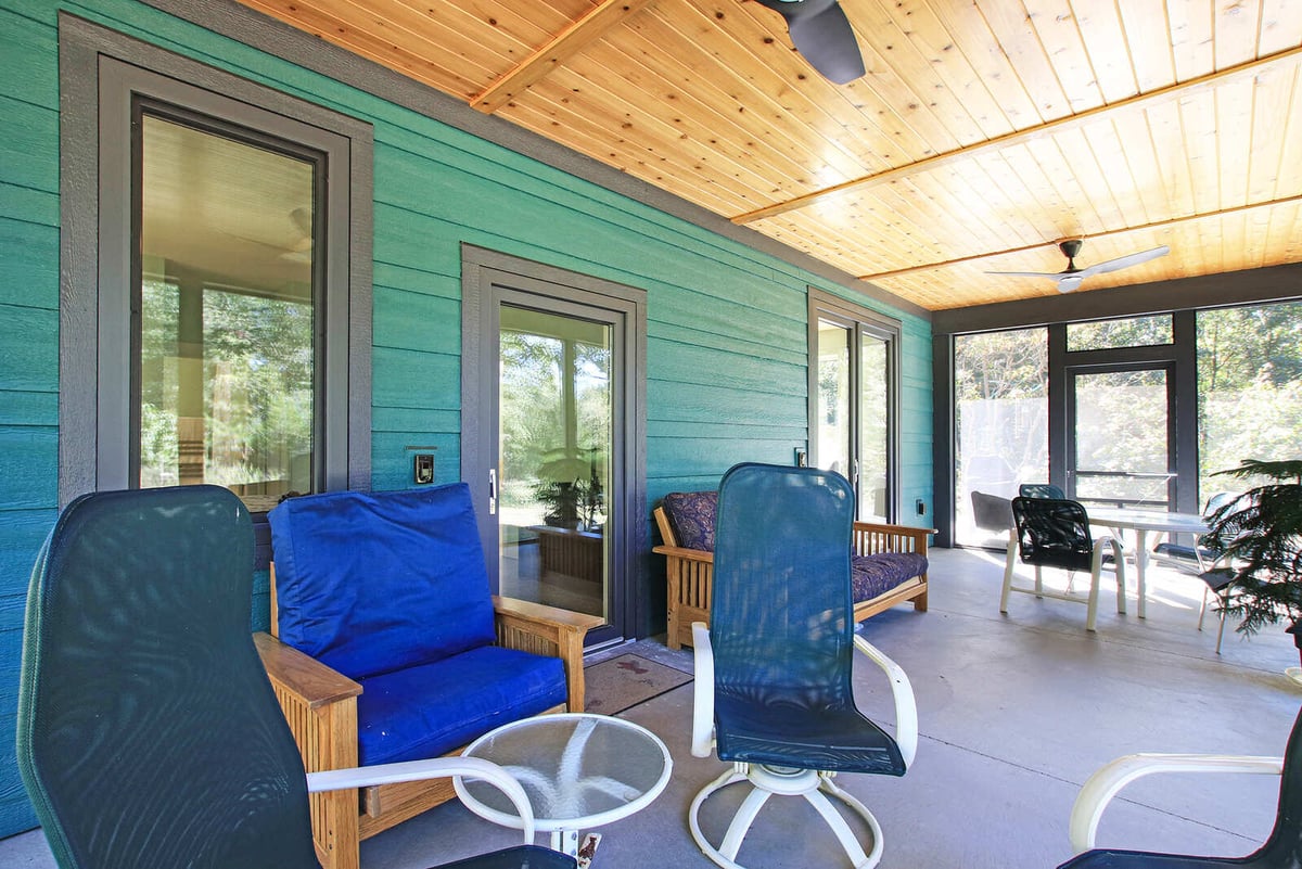 Close-up view of a screened patio with lounge seating, part of a custom West Michigan home by R Value Homes