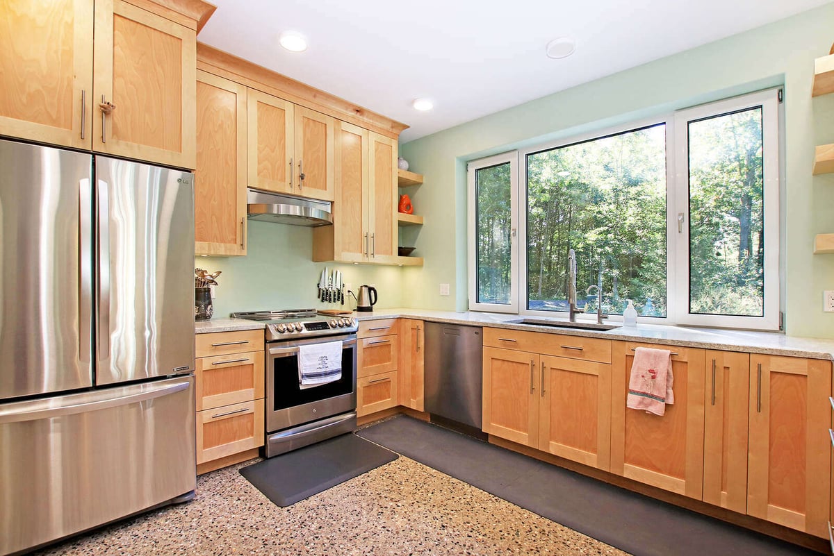 Kitchen in a custom West Michigan home by R Value Homes, featuring natural wood cabinetry and stainless steel appliances