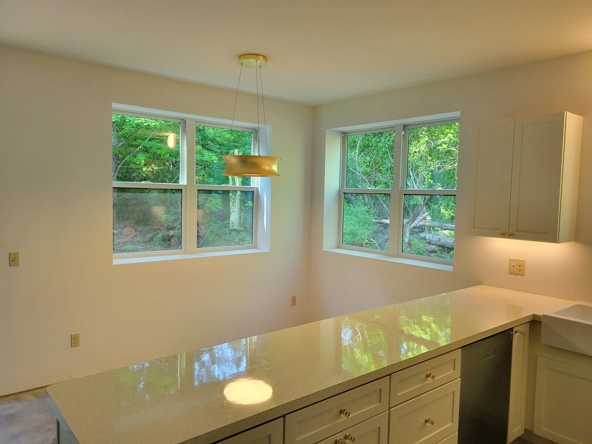 Corner view of a modern kitchen with large windows and custom cabinetry by R Value Homes in West Michigan