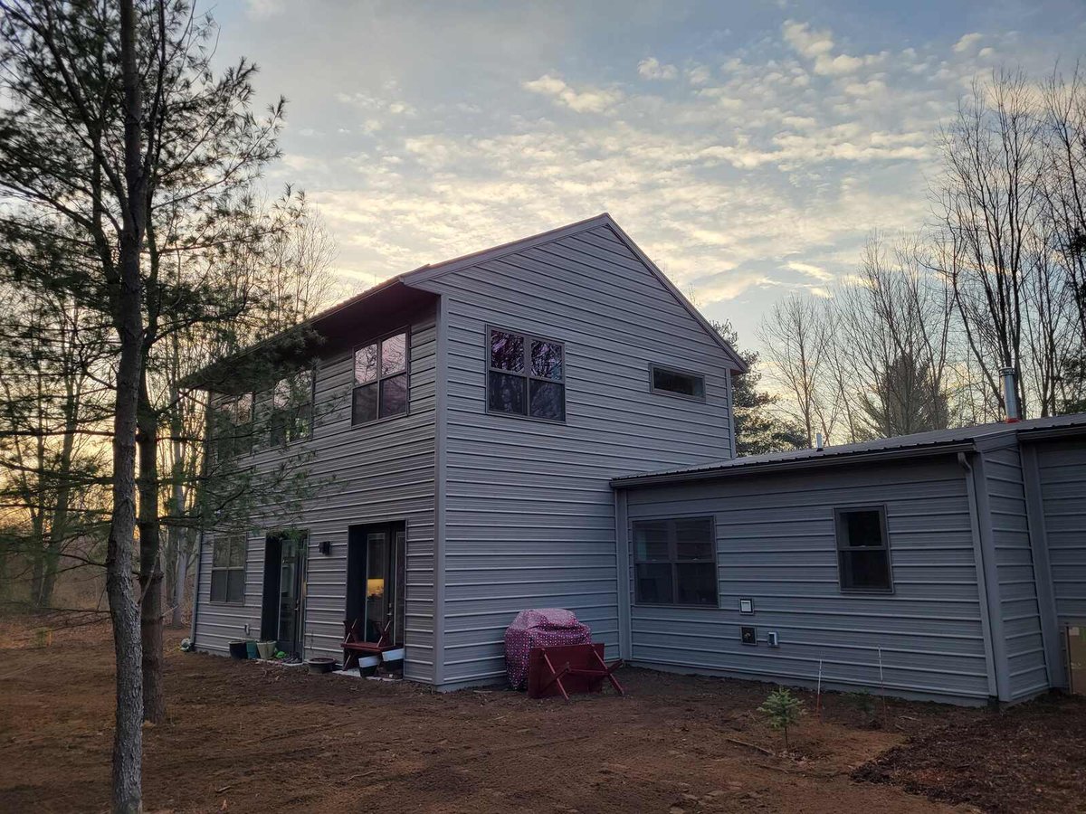 Exterior side view of a two-story home with gray siding at dusk, built by R Value Homes in West Michigan