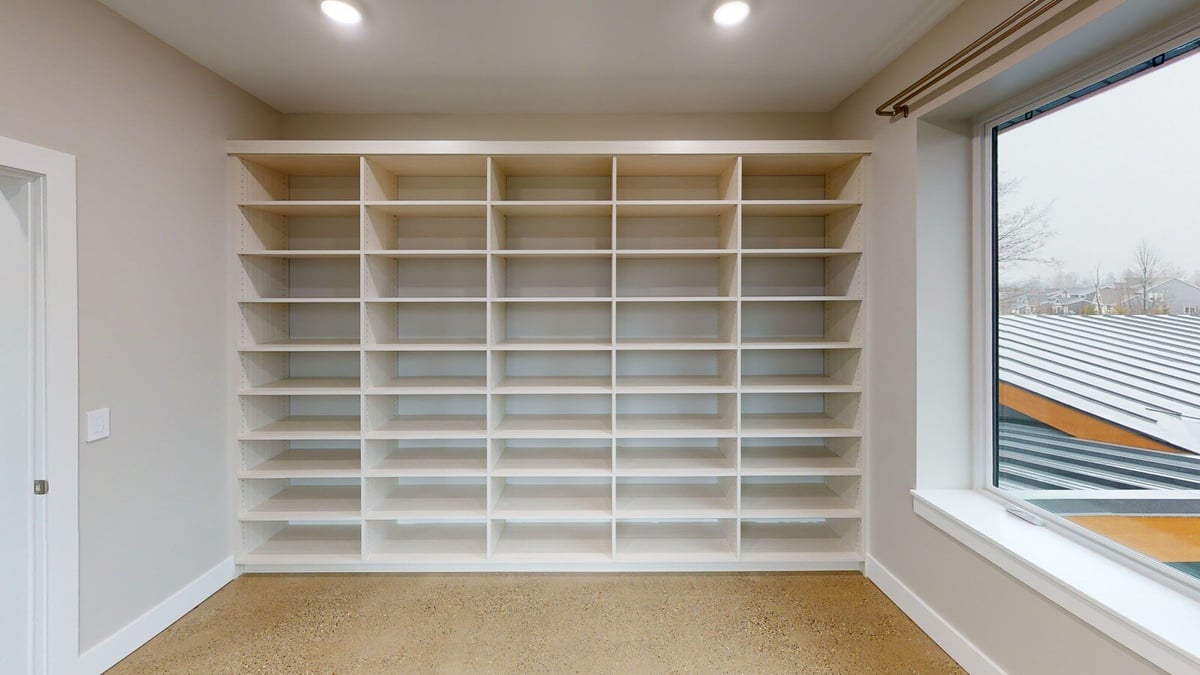 Custom-built library with white shelving and large windows, part of a West Michigan home by R Value Homes