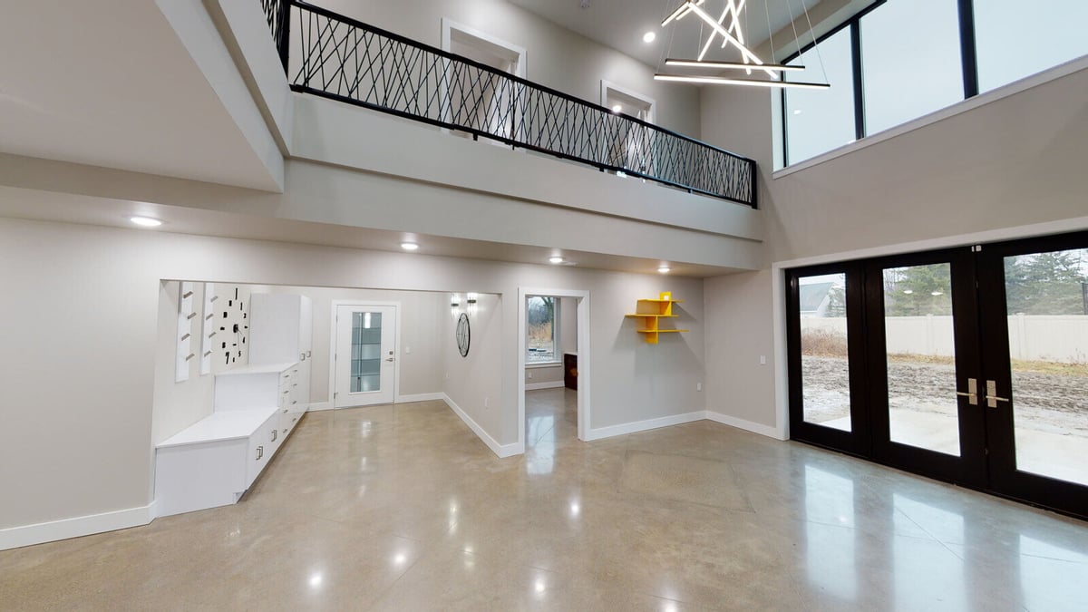 Large living area with floor-to-ceiling windows and modern lighting, part of a custom West Michigan home by R Value Homes