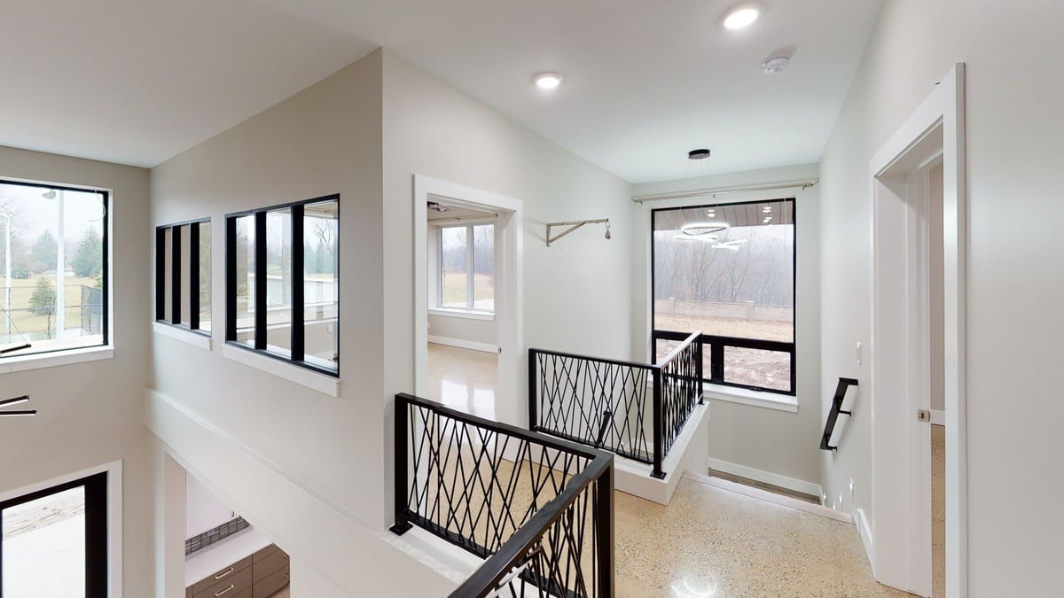 Modern hallway with sleek black railings and large windows, part of a custom home by R Value Homes in West Michigan