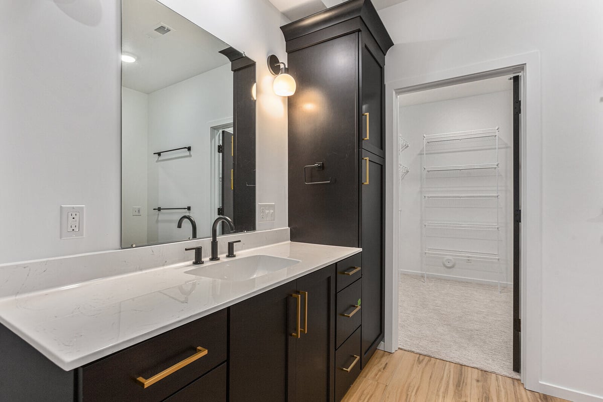 Bathroom vanity with black cabinets and gold accents by R-Value Homes in West Michigan