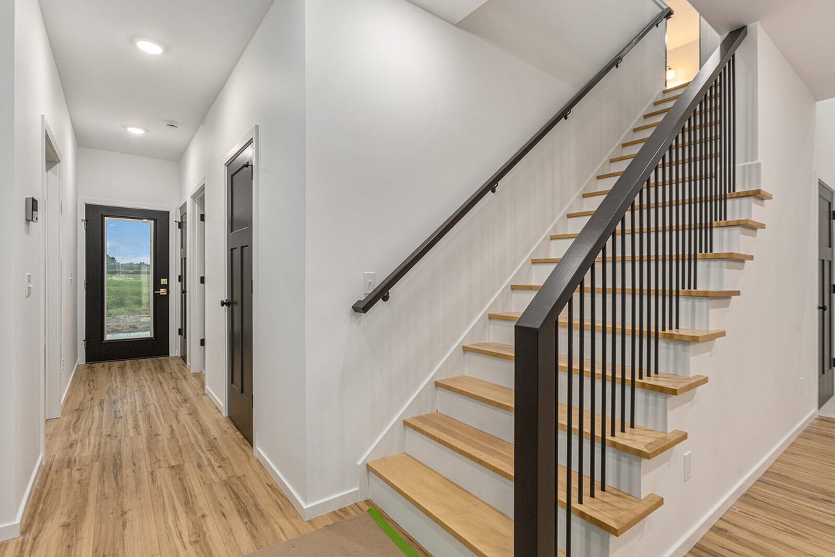 Bright hallway with wood flooring and a modern staircase by R-Value Homes in West Michigan