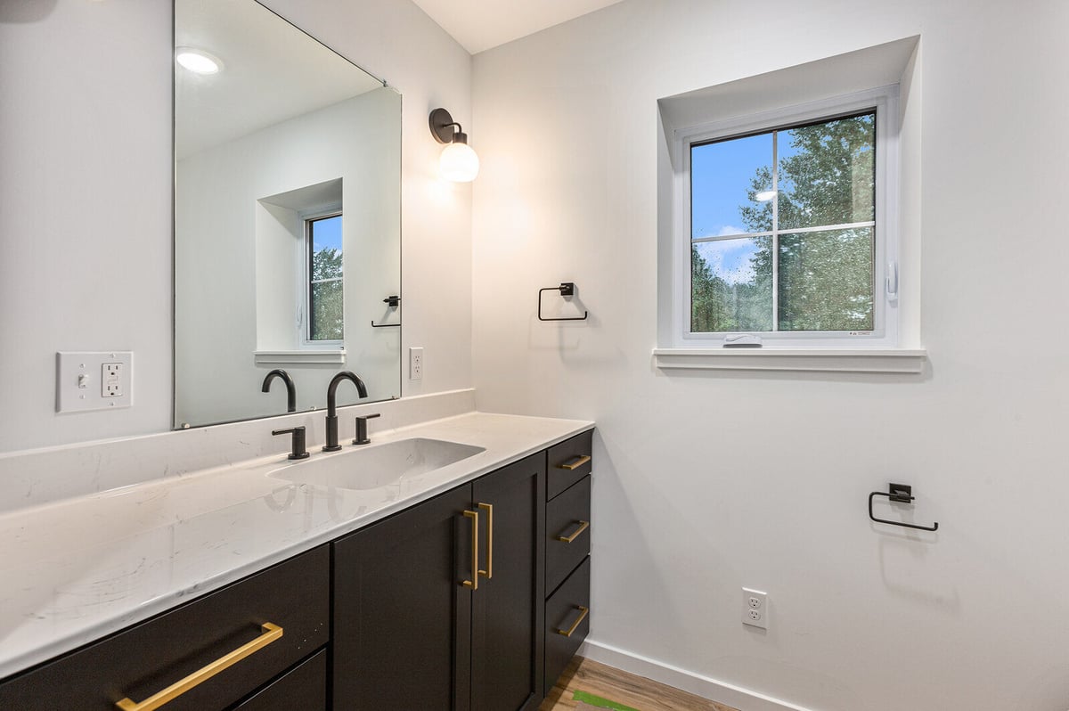 Modern bathroom with dual sinks and a large mirror by R-Value Homes in West Michigan