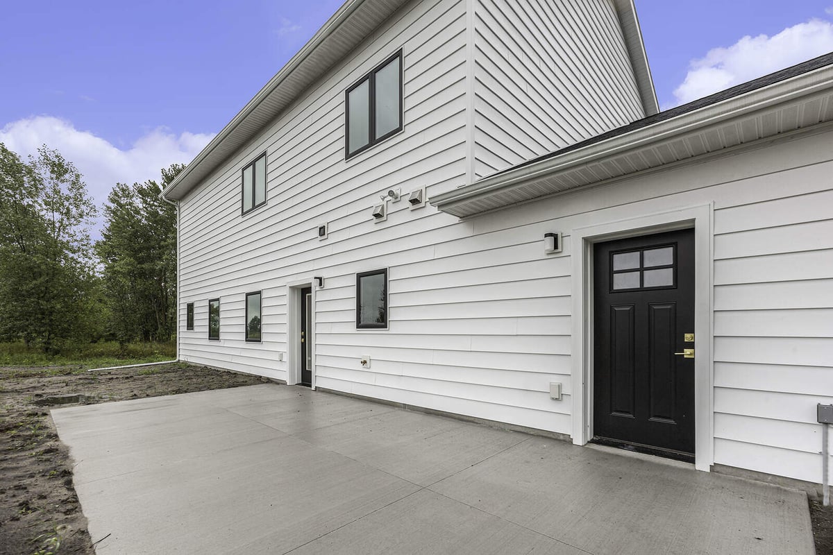 Rear patio area of a custom home with white siding by R-Value Homes in West Michigan