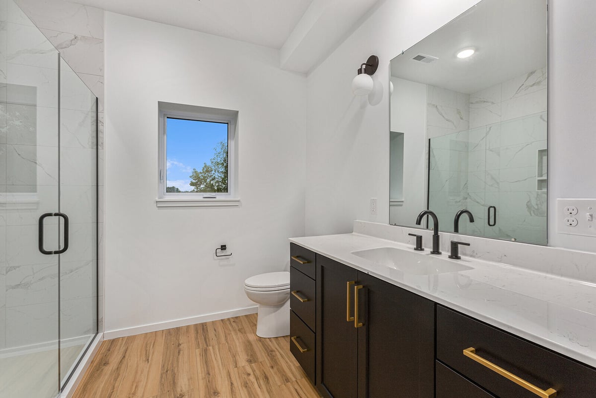 Stylish bathroom with a glass-enclosed shower and black vanity by R-Value Homes in West Michigan